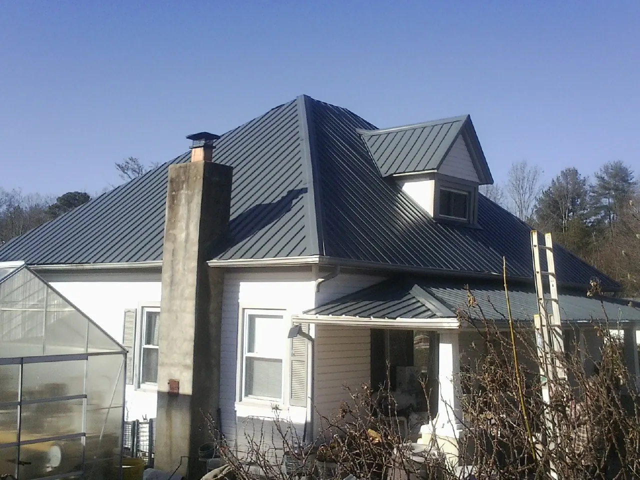 Dark blue standing seam metal roof on a white farmhouse with dormer — Slate & Tile Roof Repair by Roofing Brothers in Port Orchard