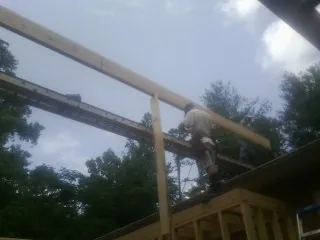 Carpenter setting a ridge beam over a new addition frame — Ice Dam Removal by Roofing Brothers in Port Orchard