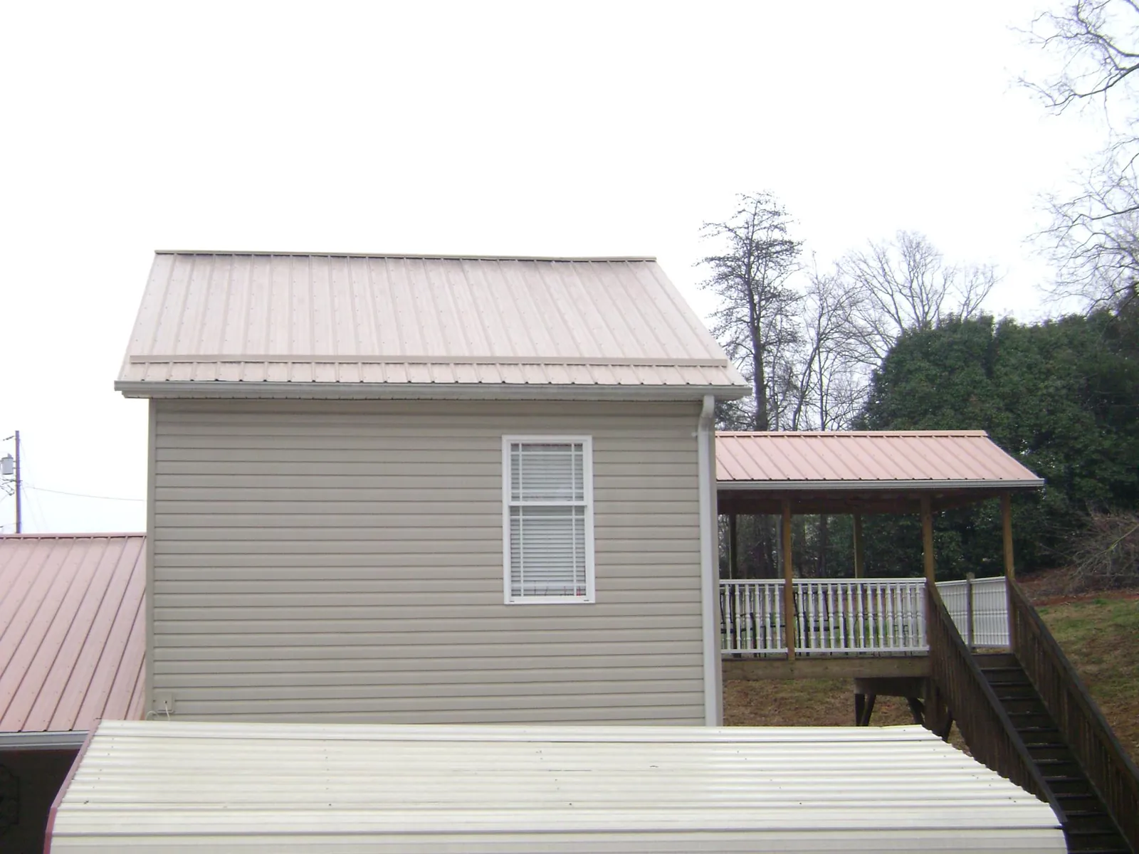 Tan metal roofs on a two story addition and attached porch, from a Roof Replacement job in Port Orchard