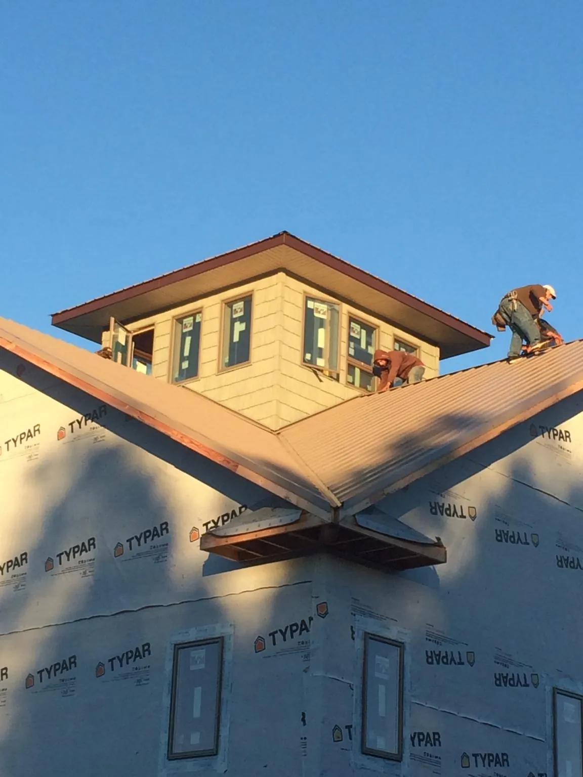 Roofers working around a rooftop cupola on a new metal roof at sunset — Roof Waterproofing in Port Orchard by Roofing Brothers